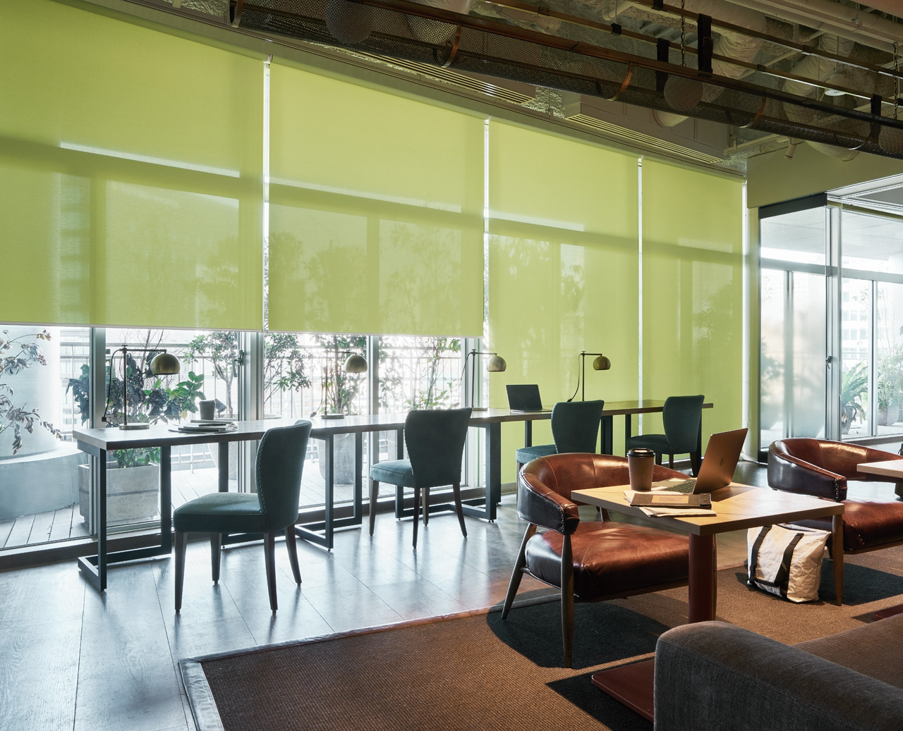 グリーンのロールスクリーンが特徴的なカフェスペース