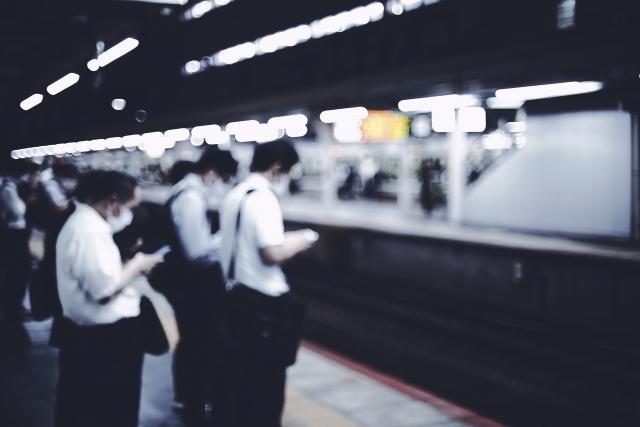 駅のホームで電車を待つ人たち