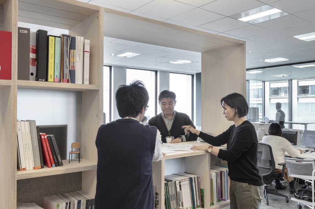 造作棚越しに立って話をするビジネスパーソン